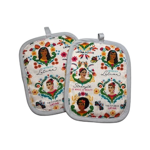 Pode incluir: Um conjunto de duas luvas de forno brancas com um design floral colorido que apresenta mulheres latinas. O texto nas luvas diz "Latina Power", "Latina Empoderada", "Strength is Magic & Beauty" e "The Future is Latina".