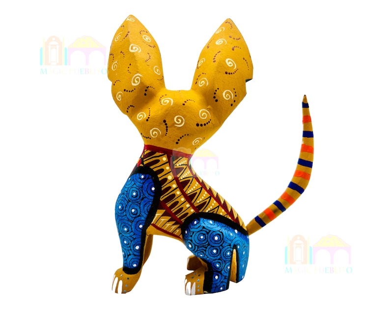 May include: A hand-painted wooden sculpture of a dog with large ears. The dog is painted in shades of yellow, blue, orange, and brown. The sculpture is a traditional Mexican folk art piece.