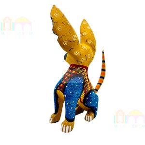 May include: A hand-painted wooden dog figurine with yellow, blue, red, and orange colors. The dog is sitting with its tail curled up and its ears perked up. The figurine is a traditional Mexican folk art piece.