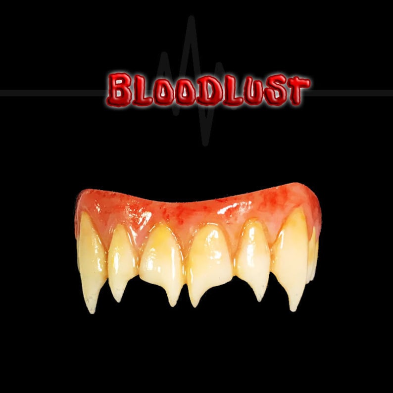 May include: A set of vampire teeth with sharp fangs, featuring a red, bloody gum line and yellowed teeth. The word "BLOODLUST" is displayed in red, 3D lettering above the teeth against a black background.