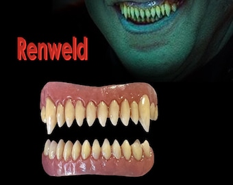 Peut inclure: Une paire de fausses dents de vampire en plastique blanc, réalistes. Les dents sont fixées sur une base rose, semblable à une gencive. Le texte "Renweld" est visible sur l'image.
