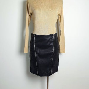 May include: A beige turtleneck sweater with long sleeves and a black faux leather skirt with zipper details.