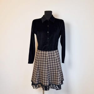 May include: A black velvet shirt with a button-up front and long sleeves, paired with a plaid skirt with a lace trim.