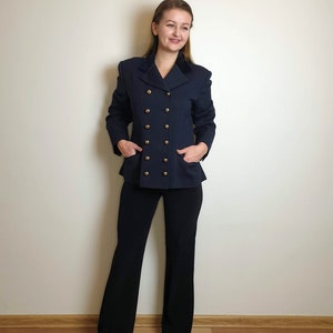 Può includere: Un blazer blu navy doppiopetto con bottoni dorati e colletto in velluto.