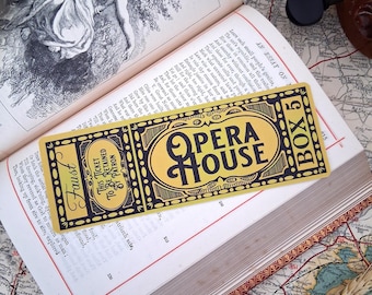 May include: A rectangular yellow and black ticket bookmark featuring the text "OPERA HOUSE", "BOX 5", and "FAUST". The design includes ornate borders and the phrase "THIS TICKET TO BE RETAINED BY PATRON" printed in a vintage, decorative style.