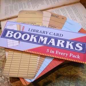 May include: A pack of five vintage-style library card bookmarks. The bookmarks are in a variety of colors, including yellow, blue, red, and brown. The pack is labeled "LIBRARY CARD BOOKMARKS 5 in Every Pack".