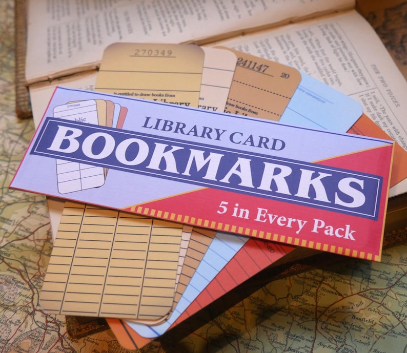 May include: A pack of five vintage-style library card bookmarks. The bookmarks are in a variety of colors, including yellow, blue, red, and brown. The pack is labeled "LIBRARY CARD BOOKMARKS 5 in Every Pack".