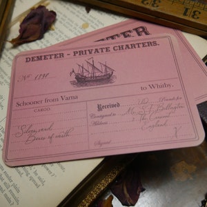 May include: A pink shipping label for the Demeter Private Charters company. The label is numbered 1897 and lists the cargo as "Silvy sand... Beres of caith..." The label is addressed to Mrs. S.F. Billington in The Crescent, England.