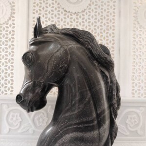 May include: A black marble horse head sculpture with intricate veining. The sculpture is a decorative piece for a home or office.