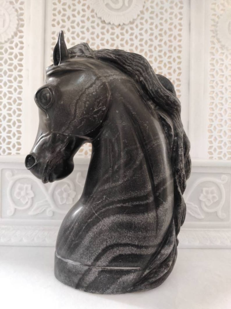 May include: A black marble horse head sculpture with intricate veining. The sculpture is a decorative piece for a home or office.