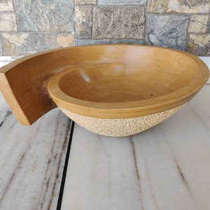 K&ouml;nnte beinhalten: Eine handgefertigte, hellbraune Steinschale mit einem einzigartigen Spiraldesign. Die Schale hat eine glatte Innenseite und eine strukturierte Au&szlig;enbasis. Die Schale misst ca. 38 cm lang, 25 cm breit und 10 cm tief.