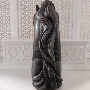 May include: A black and white marble horse head sculpture with a detailed mane. The sculpture is carved from a single piece of marble and has a smooth, polished finish.