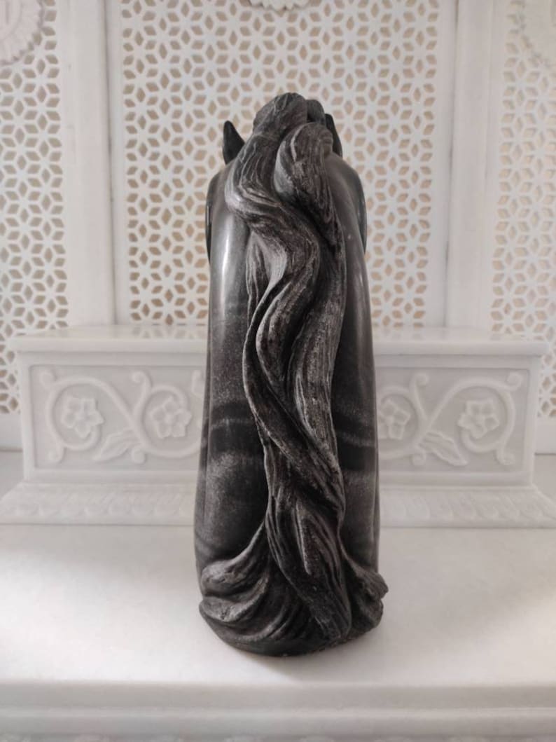 May include: A black and white marble horse head sculpture with a detailed mane. The sculpture is carved from a single piece of marble and has a smooth, polished finish.