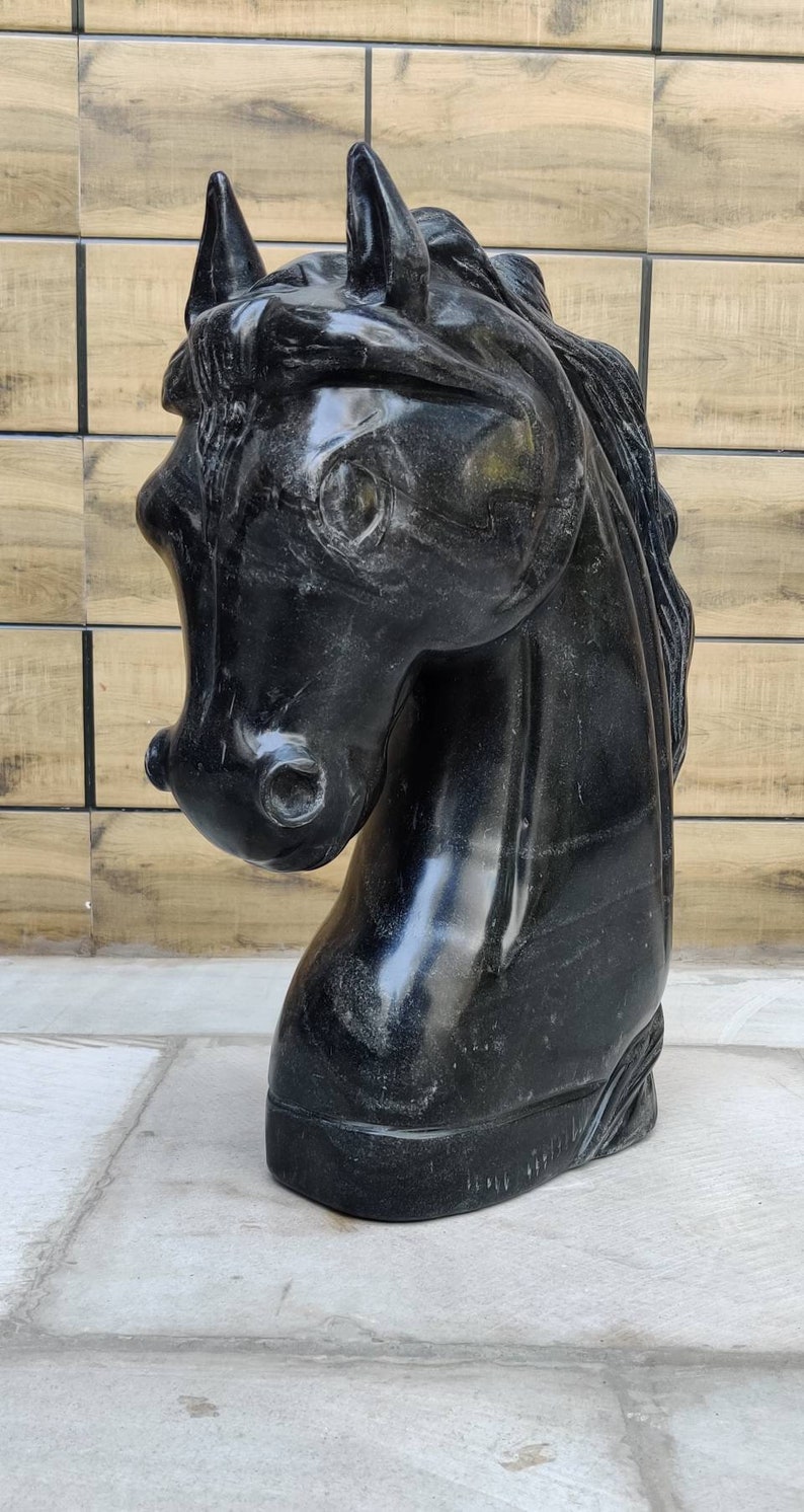 May include: Black marble horse head sculpture. The sculpture is detailed and realistic, with a smooth, polished finish.