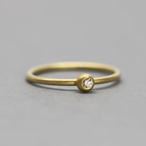 Puede incluir: Un anillo de banda de oro simple con un pequeño diamante engastado en un engaste de bisel.