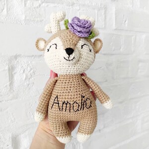 May include: A crocheted deer plush toy with a purple flower crown and the name "Amalia" embroidered on its chest.