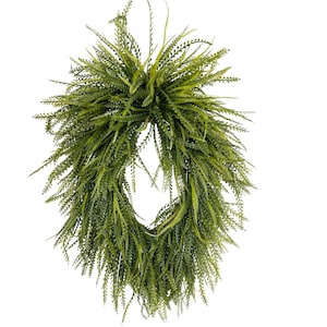 May include: An oval-shaped wreath constructed from dense, layered green fern fronds. The foliage features a mix of light and dark green tones, creating a textured, full appearance with a hollow center, designed for vertical wall or door hanging.