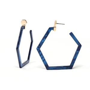 May include: A pair of blue hexagonal hoop earrings with gold accents. The earrings are made of a marbled material.