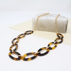 May include: A gold chain necklace with large, oval-shaped tortoise shell links.