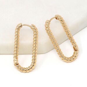 May include: A pair of gold oval hoop earrings with a twisted rope design.
