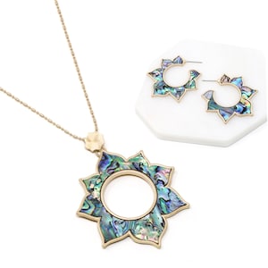 Könnte beinhalten: Ein goldfarbenes Halsketten- und Ohrring-Set mit einem großen, kreisförmigen, schillernden Blumenanhänger und passenden Ohrringen. Anhänger und Ohrringe sind aus Abalone-Schale gefertigt und haben eine goldfarbene Oberfläche.