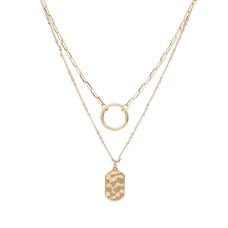 A set of double layered necklace in gold with a small disc and a hammered oval charms.