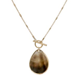May include: A gold-tone necklace featuring a delicate chain with small cylindrical accents and a toggle clasp. A teardrop-shaped pendant with a smooth, marbled brown and cream surface is suspended from the center of the toggle closure.