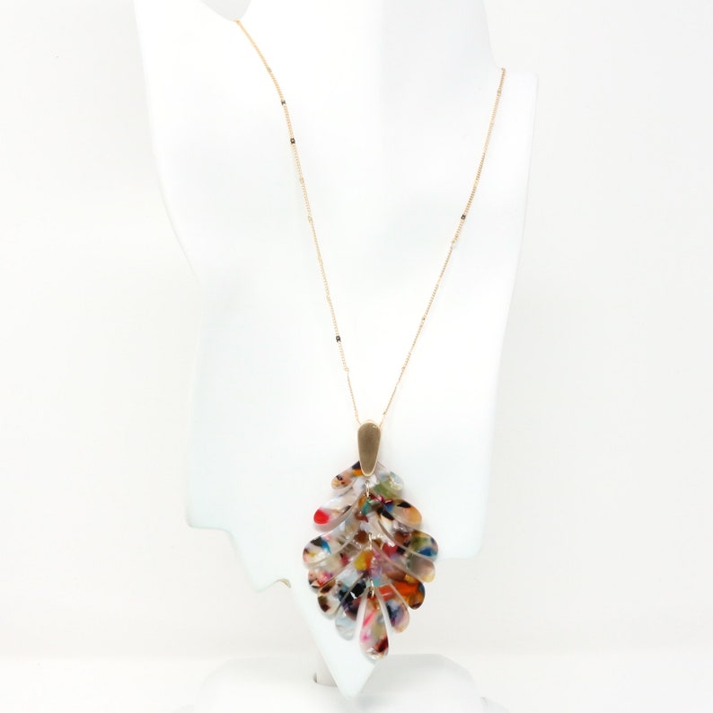 May include: A gold chain necklace with a large, multi-colored leaf pendant. The pendant is made of acrylic and has a mottled, abstract pattern.