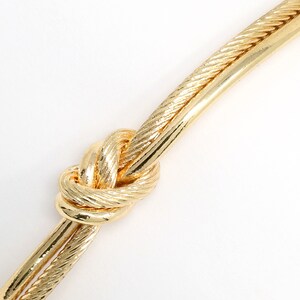 Extreme close-up of the knot detail on the textured gold rope cuff bracelet.