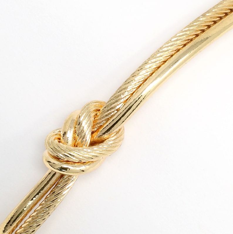 Extreme close-up of the knot detail on the textured gold rope cuff bracelet.