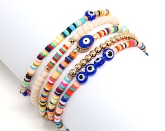 May include: A set of colorful beaded bracelets with blue evil eye charms. The bracelets are stacked on top of each other and feature a variety of colors, including pink, yellow, green, blue, and orange.