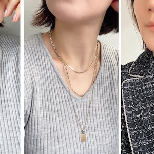 Wearing of multiple layered necklace sets in gold with small metal charms.