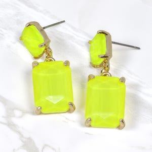 May include: A pair of neon yellow dangle earrings with gold accents. The earrings feature two rectangular shaped stones.