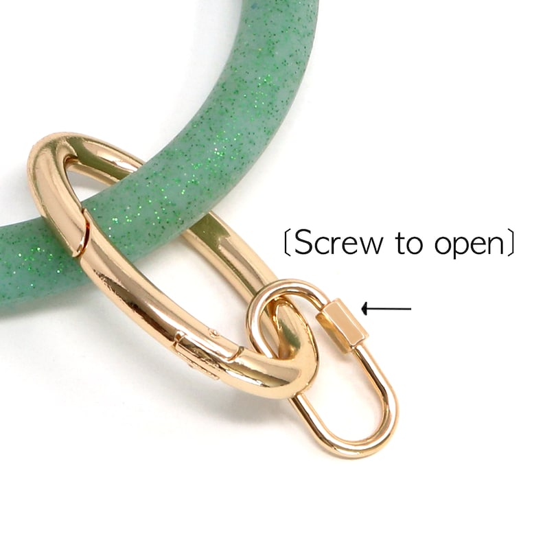 May include: A green glitter silicone key ring with a gold metal clasp. The clasp has a screw to open it.