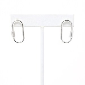 May include: A pair of silver oval-shaped earrings with a small silver bar on each earring.