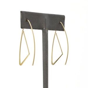 K&ouml;nnte beinhalten: Ein Paar goldene Dreiecks-Creolen. Die Ohrringe sind aus d&uuml;nnem Draht gefertigt und haben ein schlichtes, geometrisches Design.