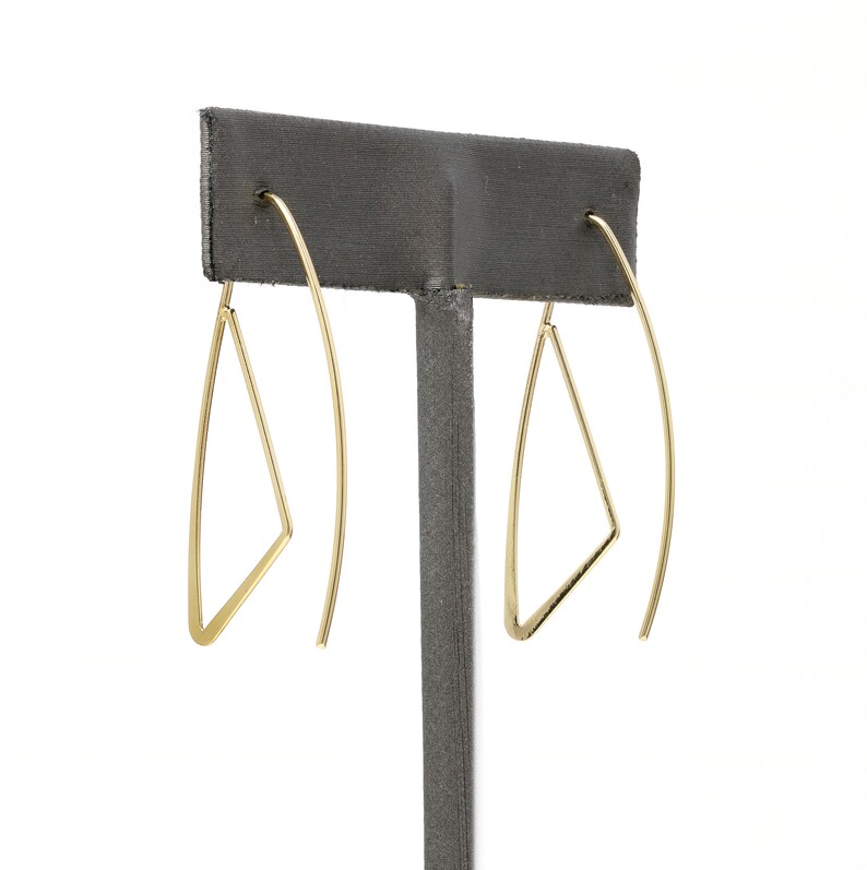 K&ouml;nnte beinhalten: Ein Paar goldene Dreiecks-Creolen. Die Ohrringe sind aus d&uuml;nnem Draht gefertigt und haben ein schlichtes, geometrisches Design.