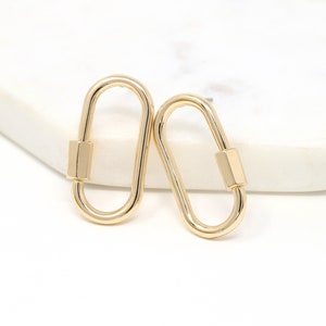 May include: A pair of gold-toned metal earrings shaped like a carabiner clip.