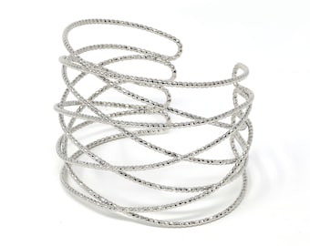 Könnte beinhalten: Ein silbernes Drahtarmband mit Perlenmuster. Das Armband besteht aus mehreren miteinander verflochtenen Drahtsträngen.
