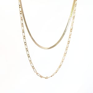 May include: A gold layered chain necklace with a thin, flat snake chain and a thicker, more textured chain.