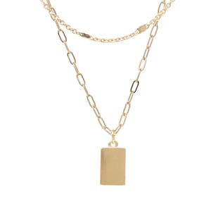 A gold chain necklace with a rectangular pendant. The necklace has two chains, one thicker than the other.