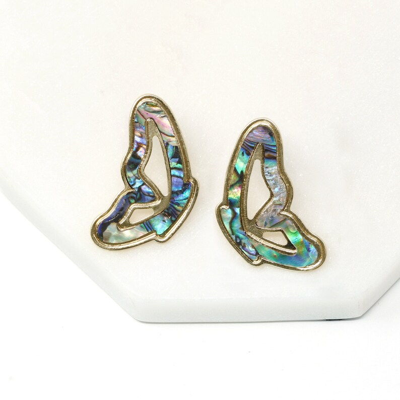 Pode incluir: Um par de brincos de borboleta de ouro com incrusta&ccedil;&otilde;es de madrep&eacute;rola de abalone iridescente. Os brincos s&atilde;o um design delicado e feminino.