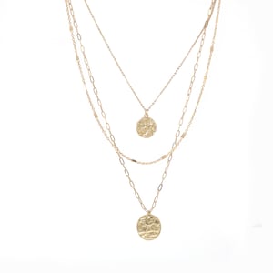 A set of triple layered necklace in gold with two small hammered circle charms.