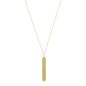 May include: A gold-colored necklace with a long, rectangular pendant. The pendant is vertically oriented and has a brushed metal texture. The chain is delicate and connects to the pendant at the top. The necklace is displayed against a white background.