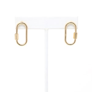 May include: A pair of gold oval-shaped earrings with a small gold bar on each earring.