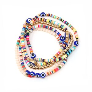 May include: A set of colorful beaded bracelets with gold accents and blue evil eye charms. The bracelets are layered and feature a variety of colors, including pink, yellow, blue, green, and orange.
