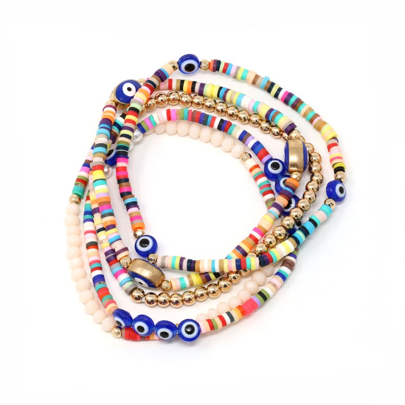 May include: A set of colorful beaded bracelets with gold accents and blue evil eye charms. The bracelets are layered and feature a variety of colors, including pink, yellow, blue, green, and orange.