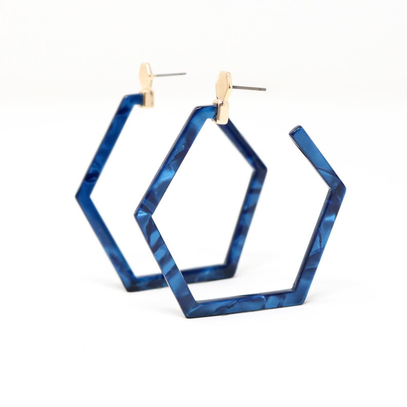 May include: A pair of blue hexagonal hoop earrings with a marbled pattern. The earrings have a gold-toned post.