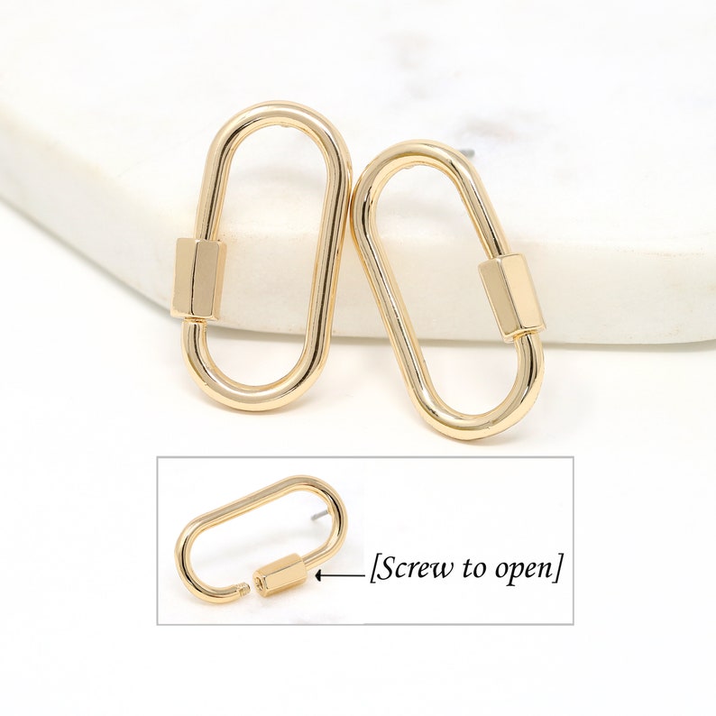 May include: A pair of gold-toned oval-shaped earrings with a screw closure. The earrings are open and the screw is visible. The text "Screw to open" is visible in the image.