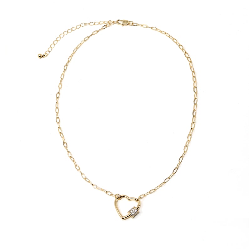 May include: A gold chain necklace with a heart-shaped pendant featuring a small clear crystal.